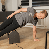 Person performing a side plank on a wooden block indoors.