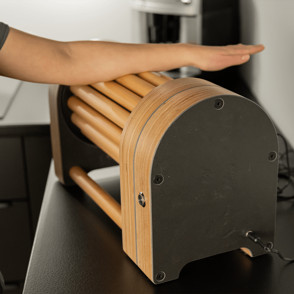 Person using a wooden device with cylindrical rollers on a table